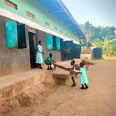 Students carrying furniture in a classroom at Kyansi school in Uganda.